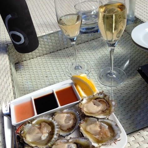 Plate of raw oysters and dipping sauces with two glasses of sparkling wine