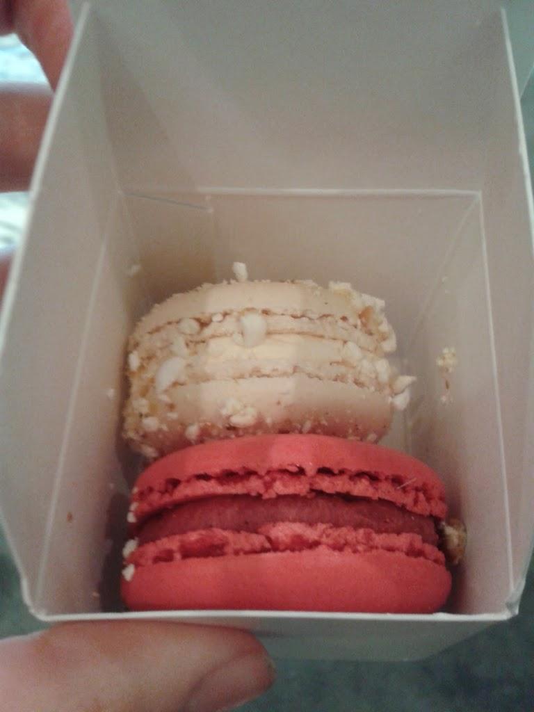 one pink and one white macaroon inside a small white box