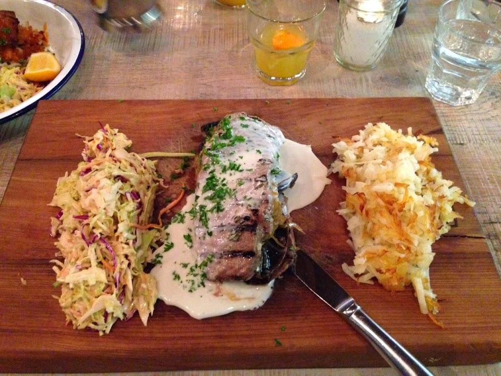 steak served on wooden platter with coleslaw and potato hash