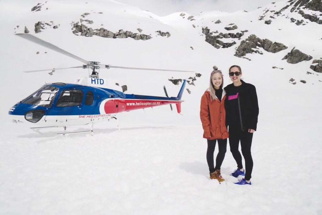 two girls and helicopter on snow during franz josef helicopter ride