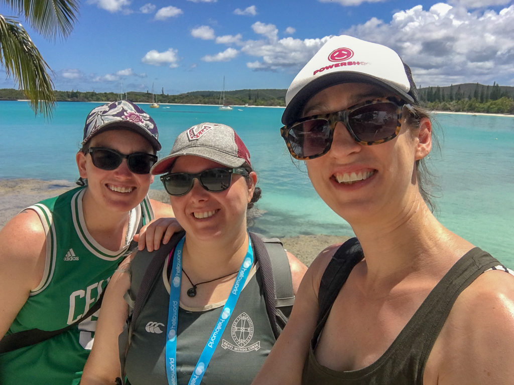 selfie of three young woman with sea, boats and green island in background