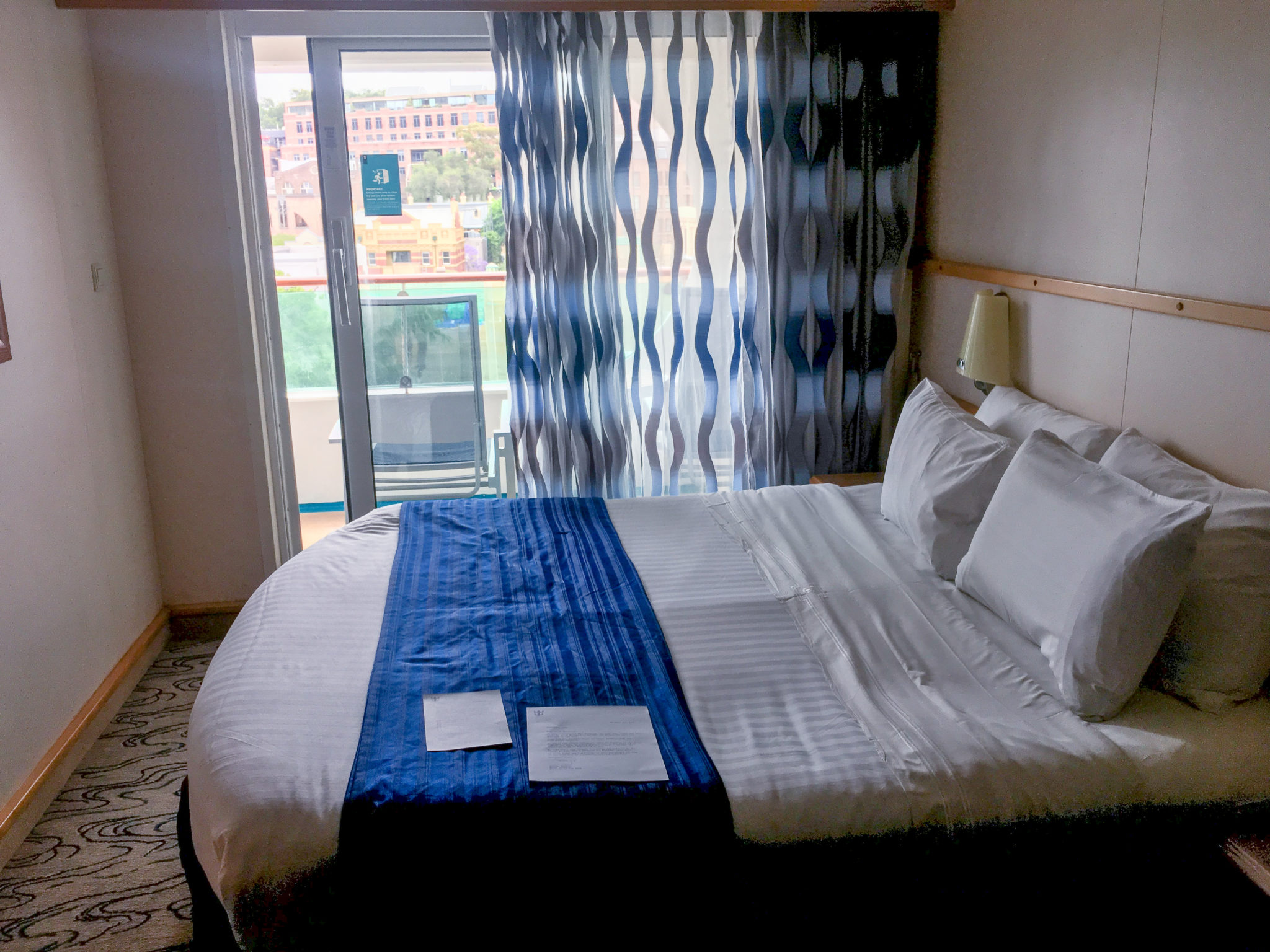 Bed in front of glass sliding doors on cruise ship