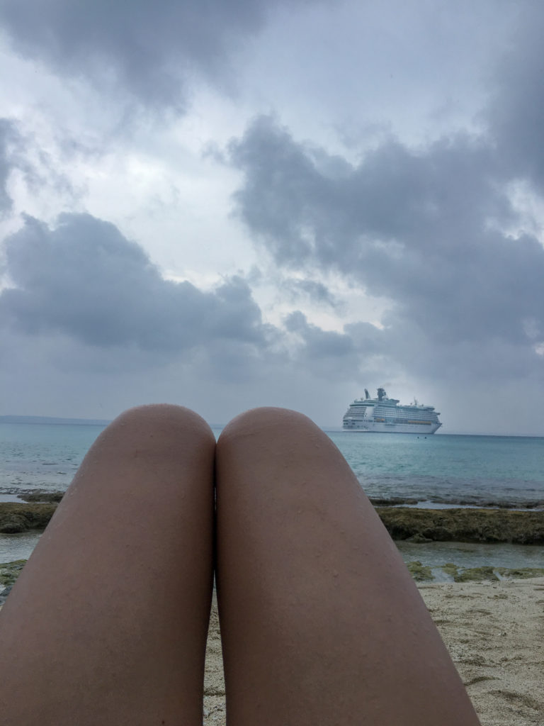 legs on beach with cruise ship in background