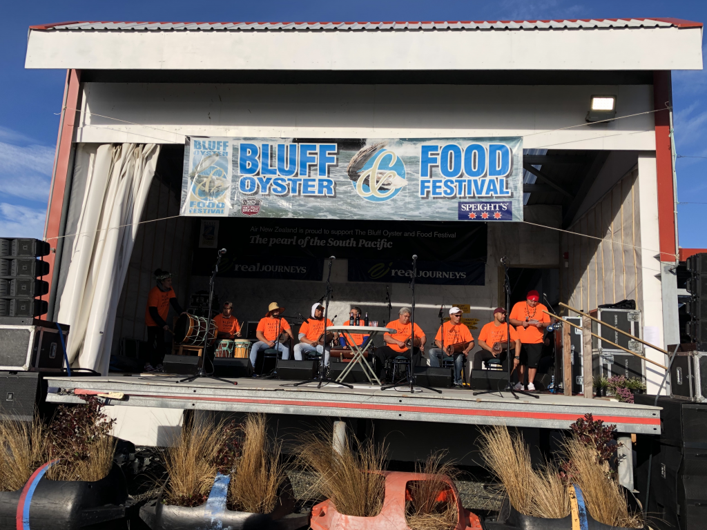 group of nine people in orange tshirts on stage at the Bluff Oyster & Food Festival 2019
