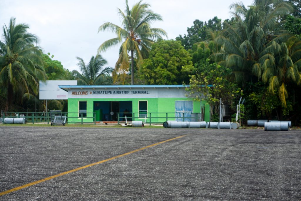 small green airport building amongst island palm trees