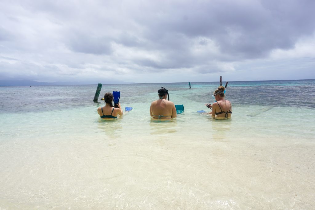 three women preparing to snorkel in clear water