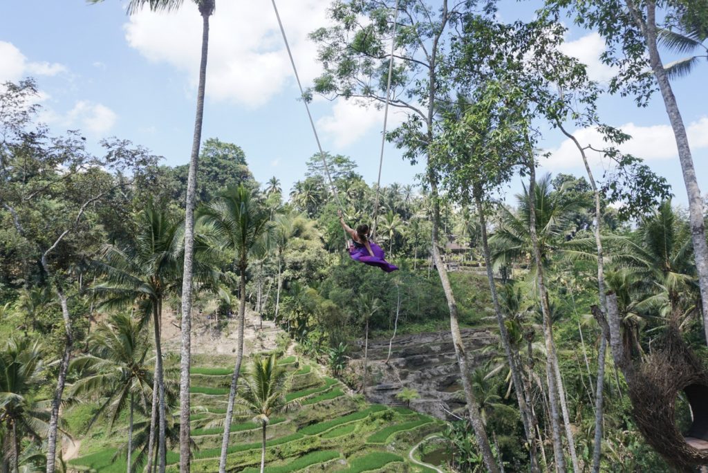 young woman in purple skirt on tegalalang rice terraces swing