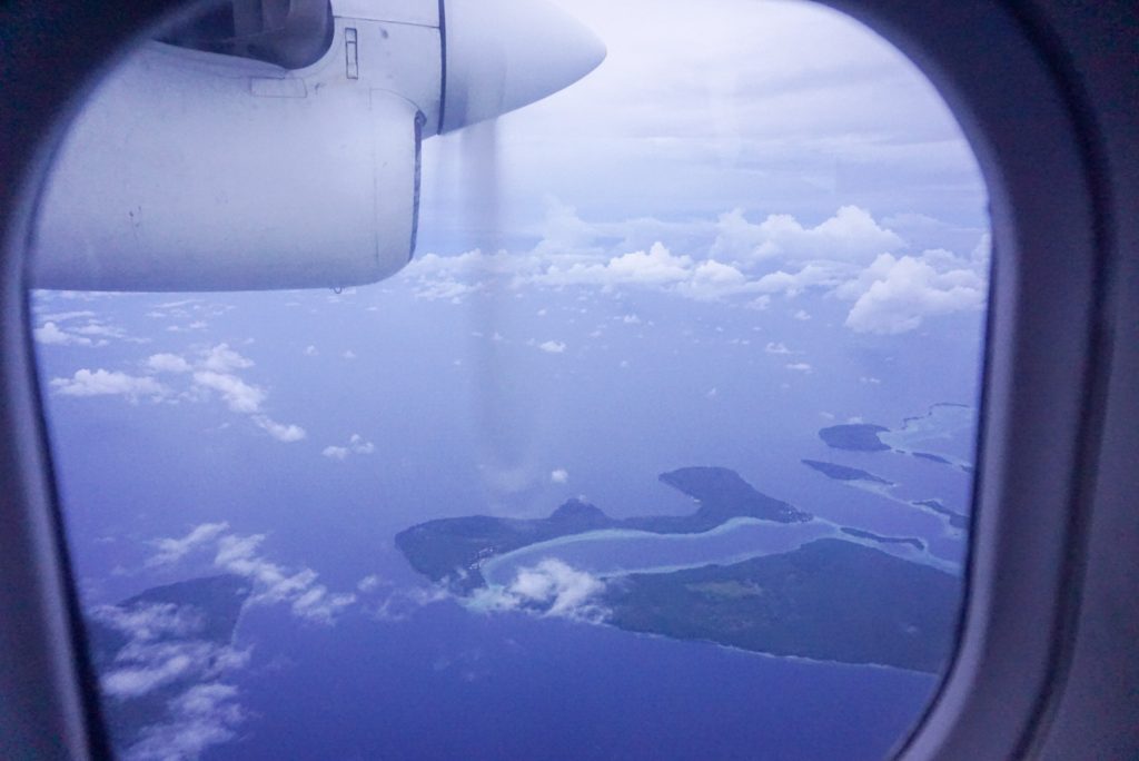 view of pacific islands and plane propeller out window in blue sky