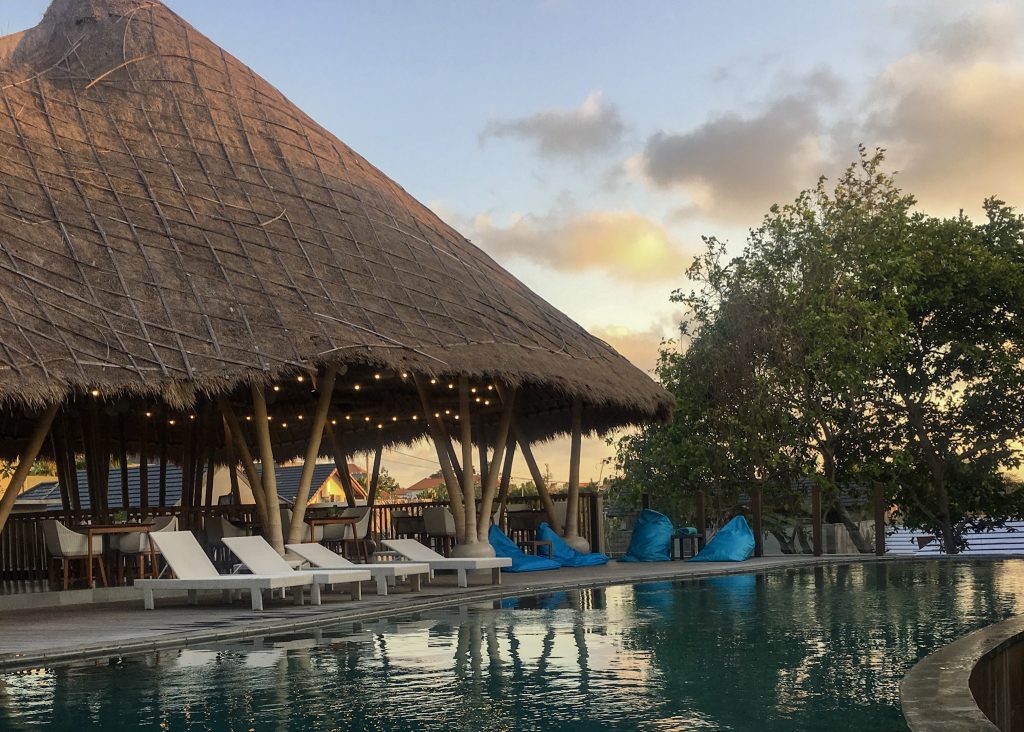 pool in evening with four white sunchairs under hut