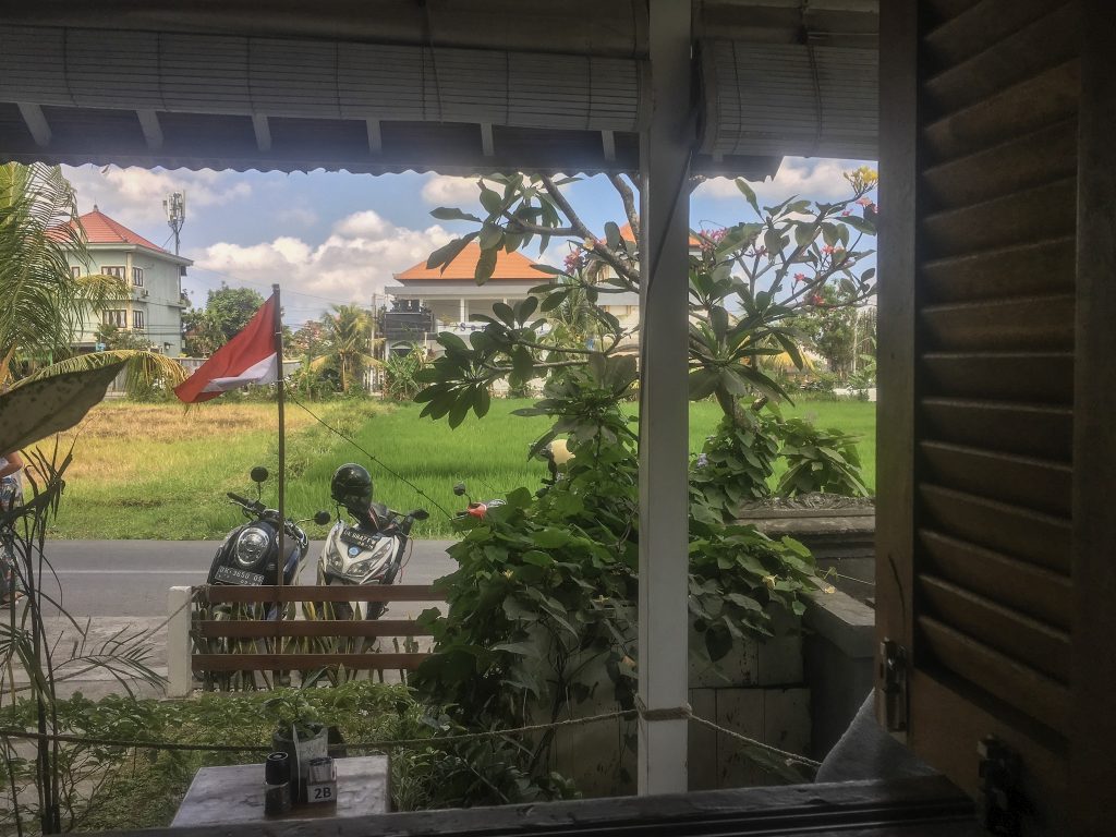 view of a rice field from a villa in bali with two scooters parked out front