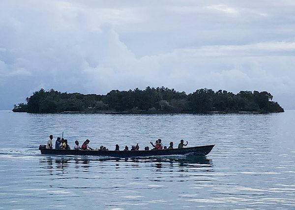 group of people in a small boat with two islands in background in the Solomon Islands