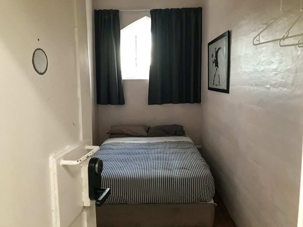 Double bed with striped blue duvet in converted jail cell