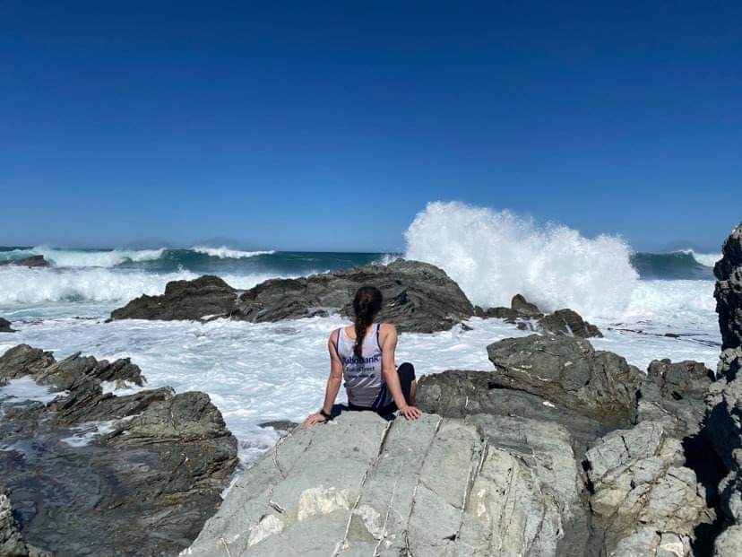Young woman sitting on rocks on Tora Coast Wairarapa