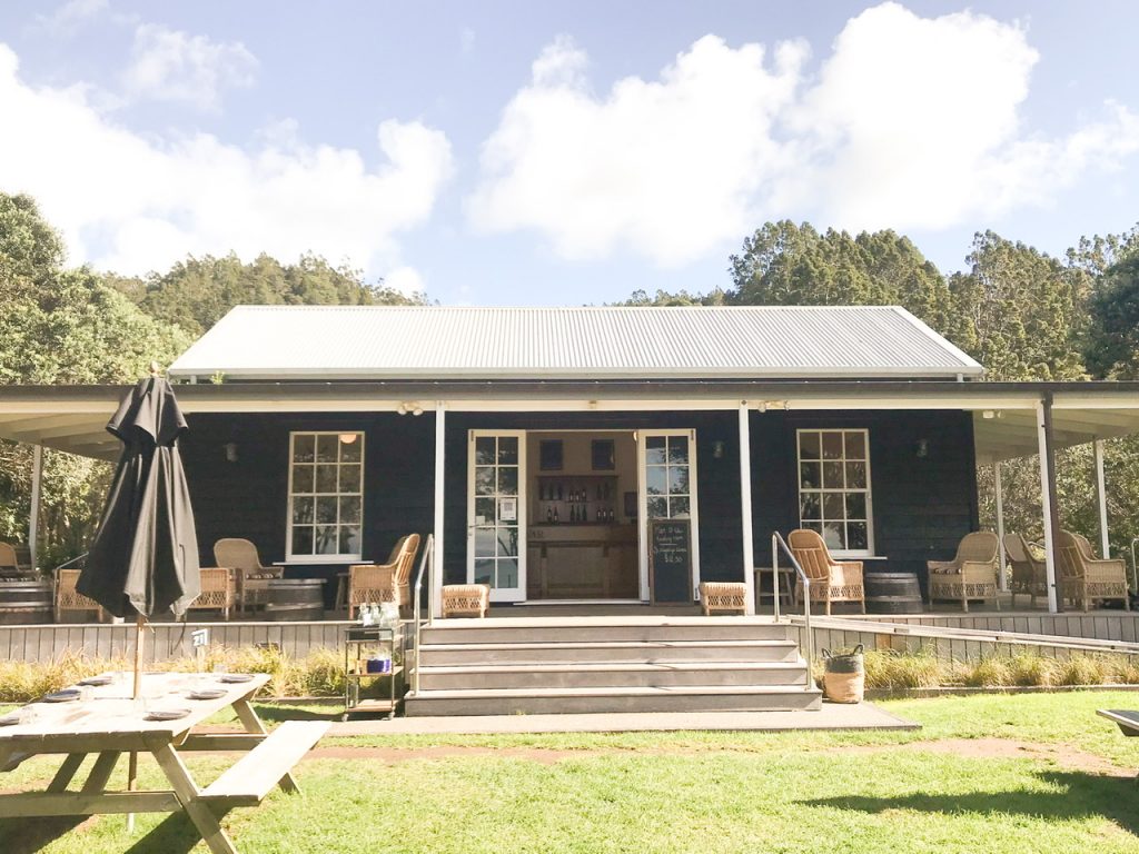 Black wooden Cellar Door building with central glass doors and windows either side at Man O War Winery Waiheke Island