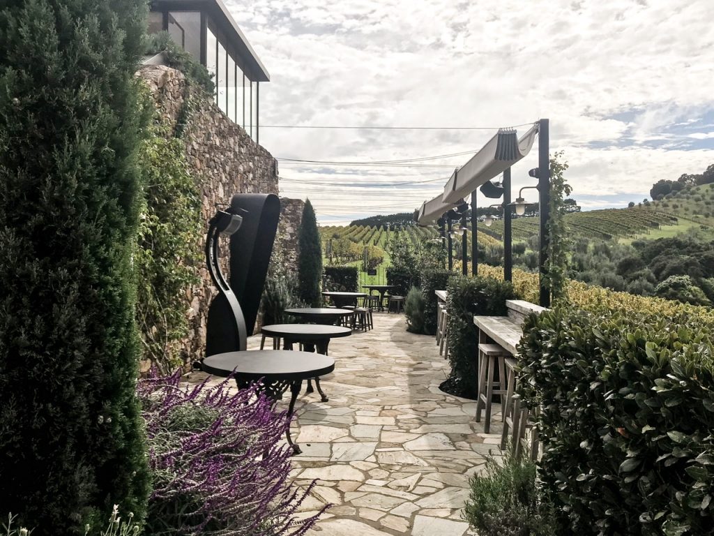 Exterior of Tantalus Estate Waiheke Island cellar door with tables, brickwork and wine vines in background