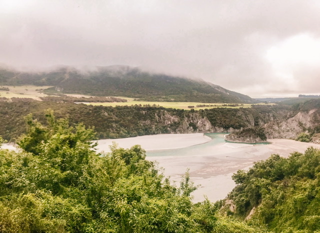 Waimakariri River with green native bush in the foreground and mountainous banks behind
