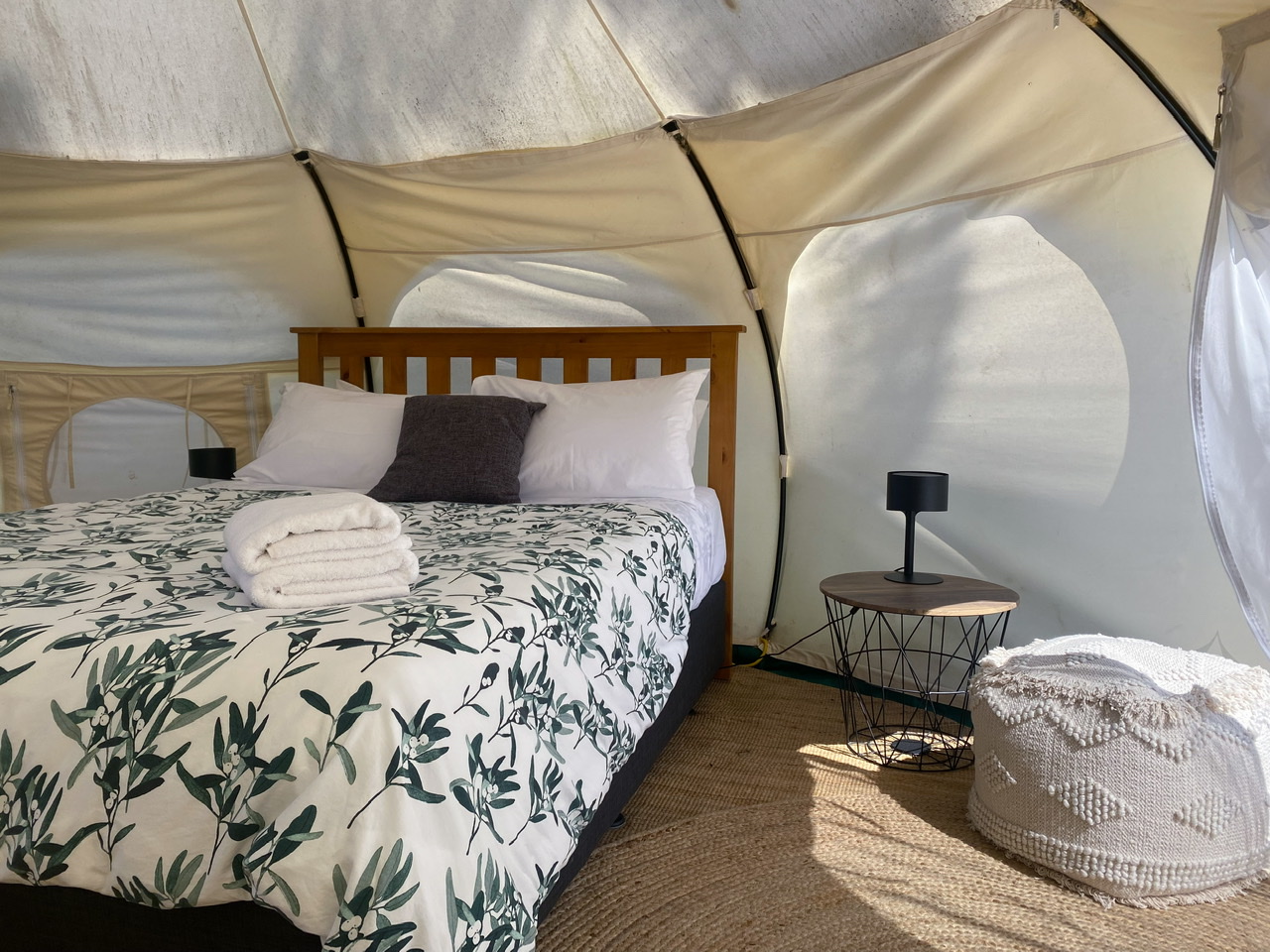 Double bed with towels stacked on it inside a glamping tent