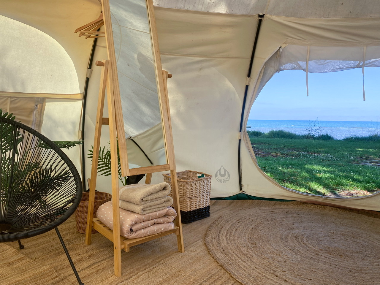 Interior of glamping tent with open door looking out to ocean