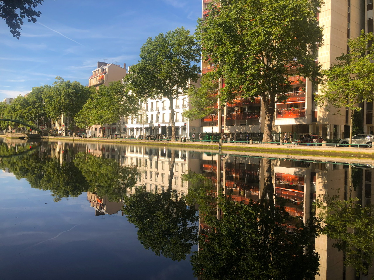 Canal saint martin in paris with buildings on far side of canal reflected in canal