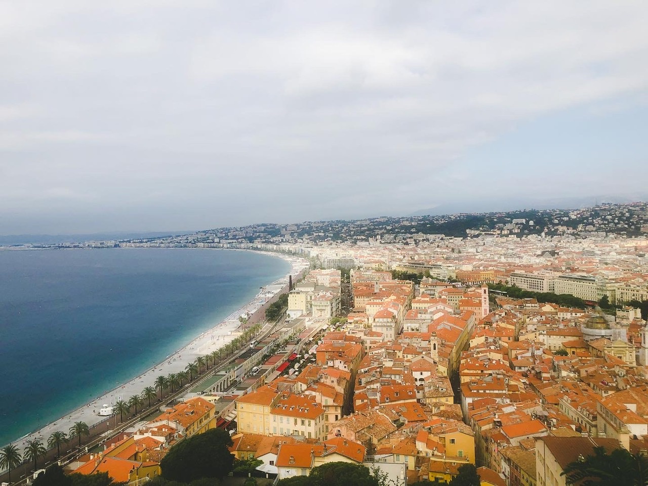 View of Nice Coastline with blue sky and water, sandy beach and largely orange buildings