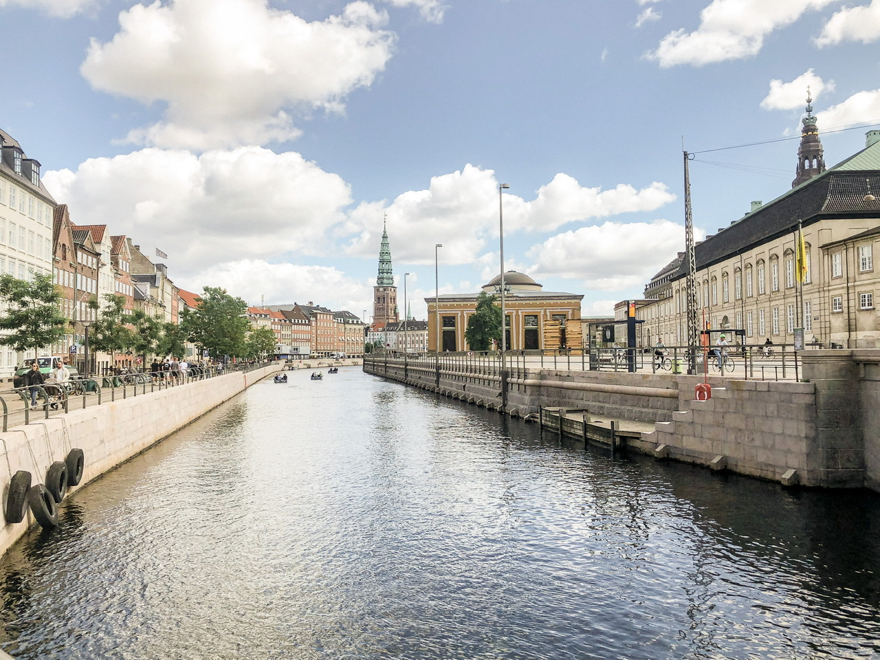 Canal in Copenhagen with waterfront buildings and church spire visible alongside