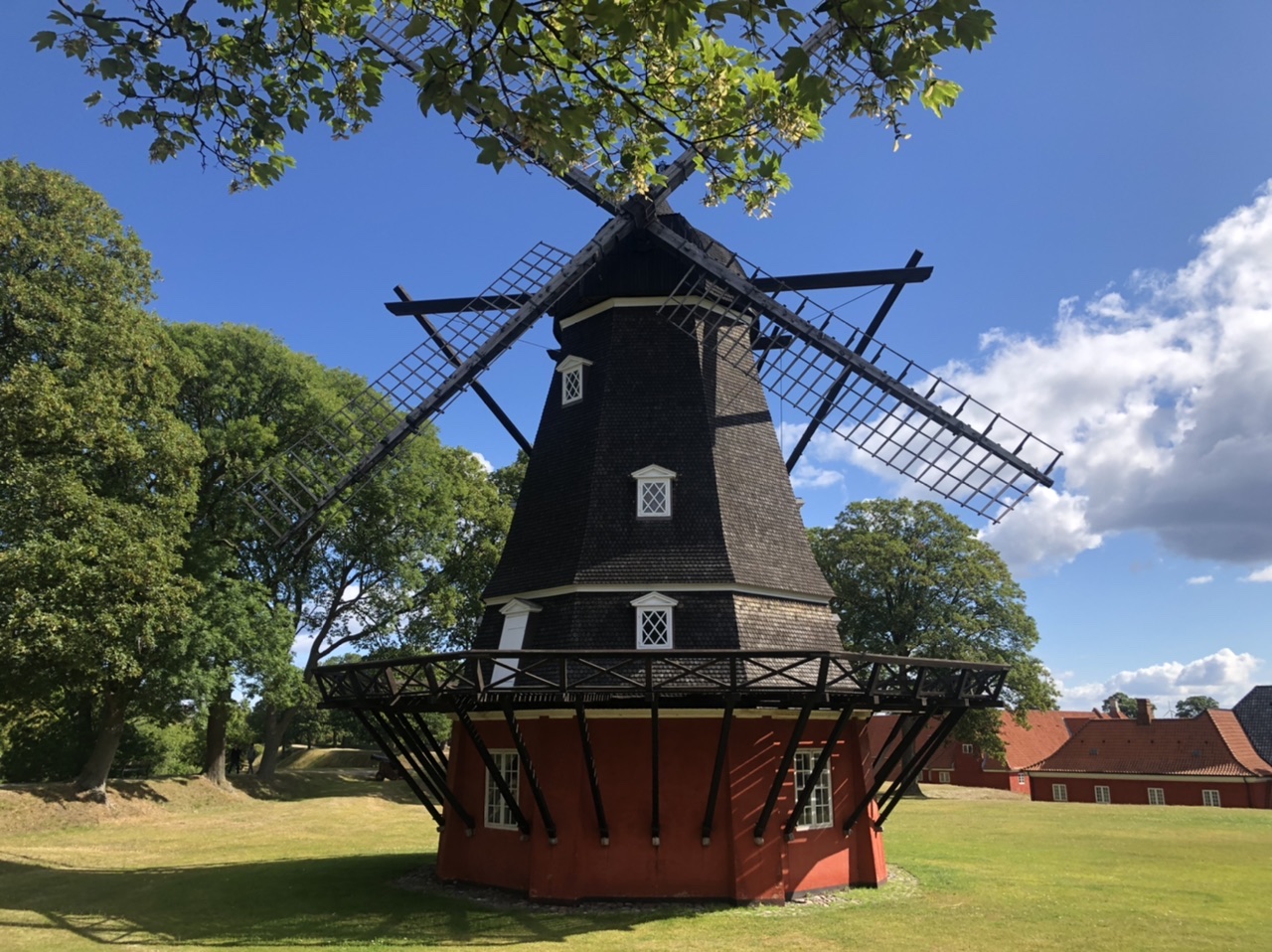 traditional wooden windmill on green grass surrounded by green trees