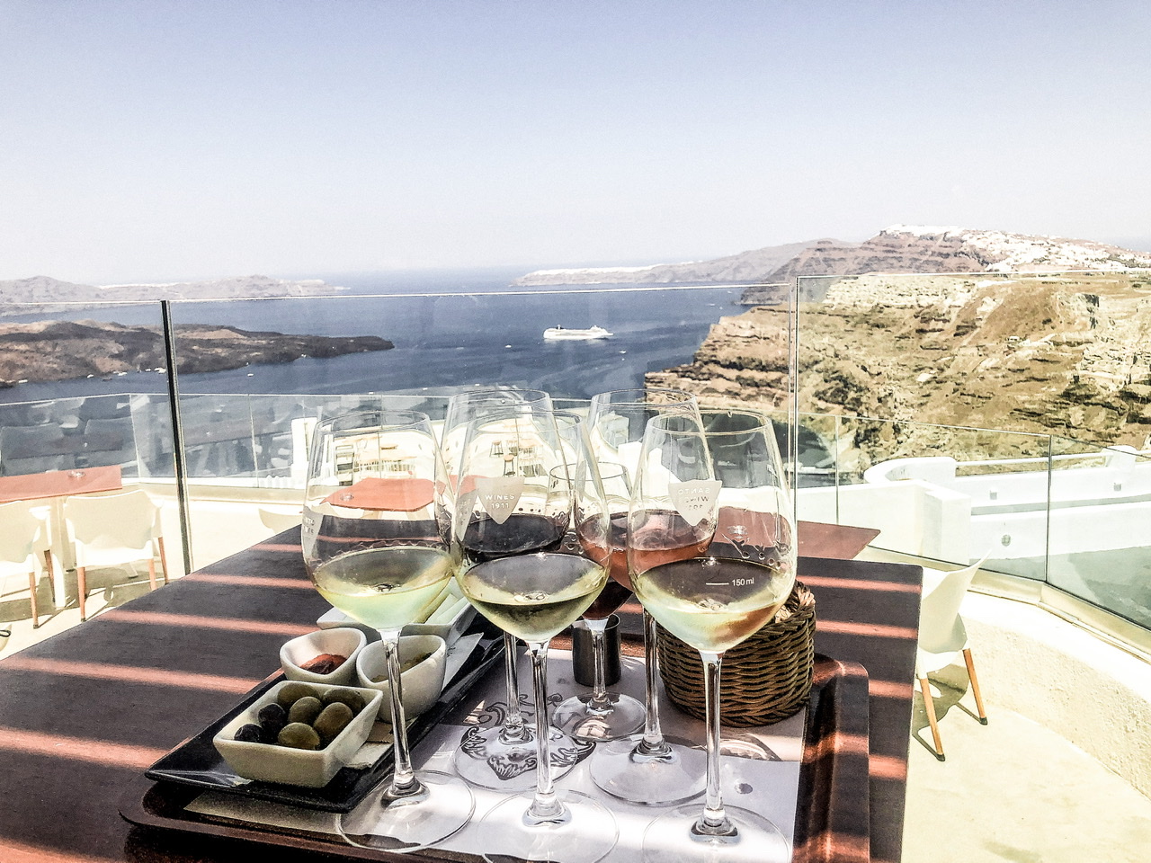 6 wine tasting tray at Santo Wines Santorini with view of water and volcanic rock cliffs