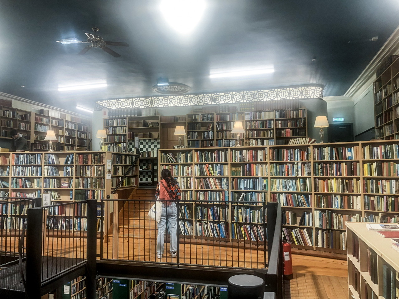 A woman browses full bookshelves inside an old bookshop