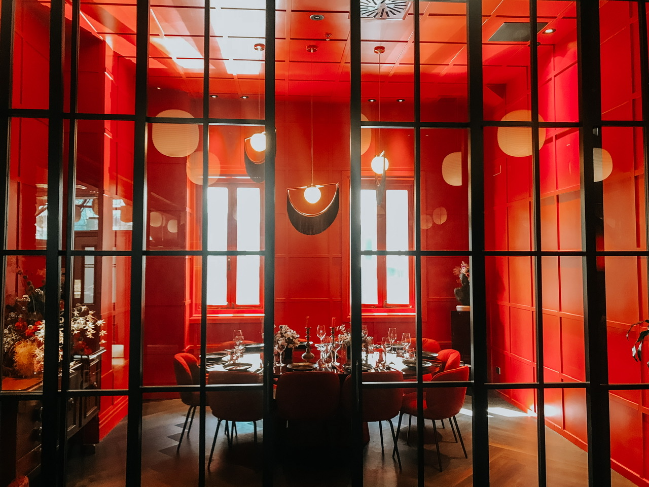 Private dining room with round table set for around 10 people with red chairs and walls behind ajar glass sliding doors