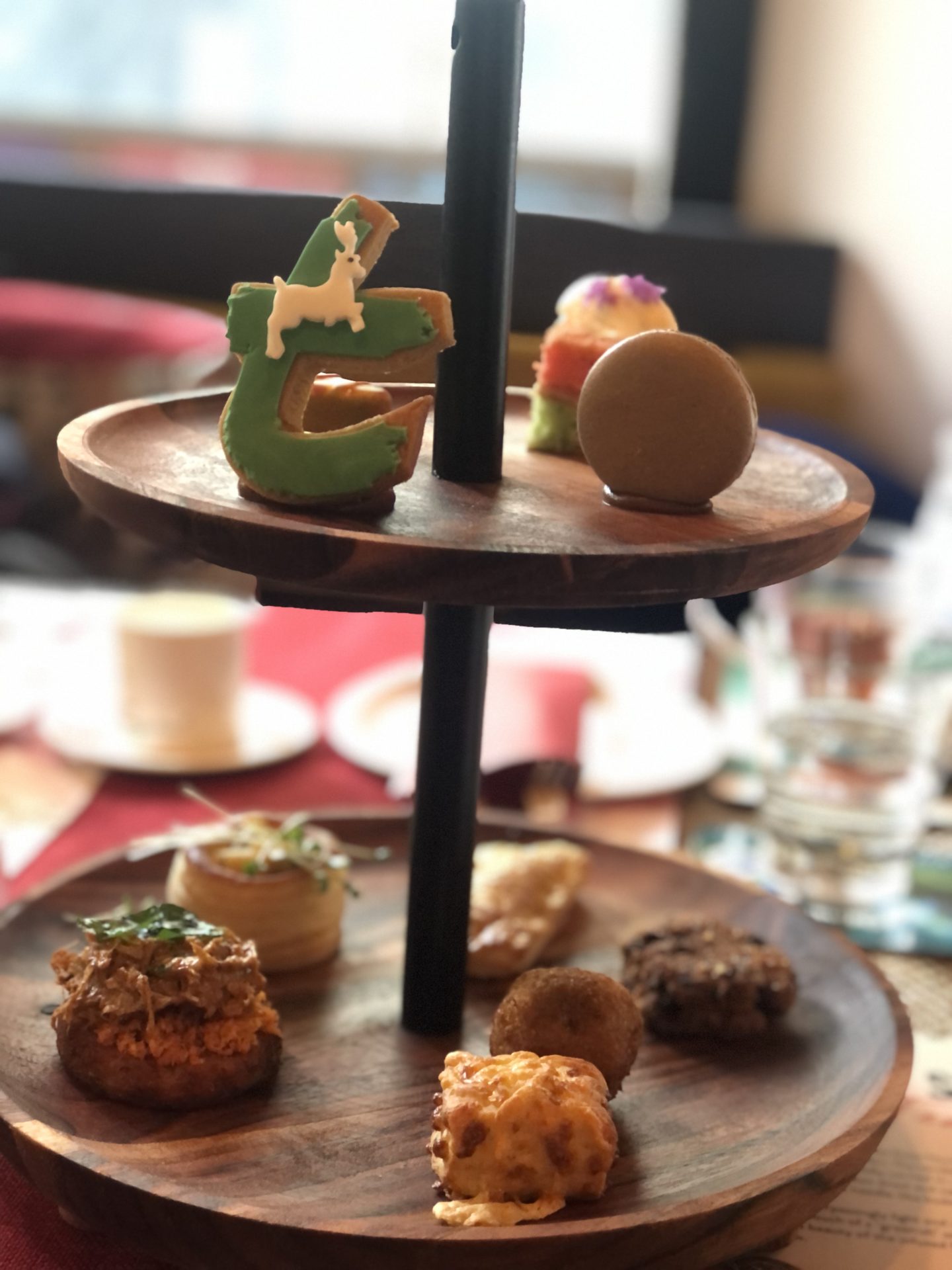 Two-tiered high tea stand with six savoury items on the bottom plate and four sweet items on the top