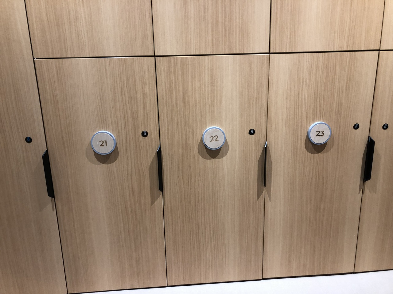Light-wood coloured lockers at Ōpuke Thermal Pools and Day Spa. Numbers 21-23 are pictured and they have contactless key entry.