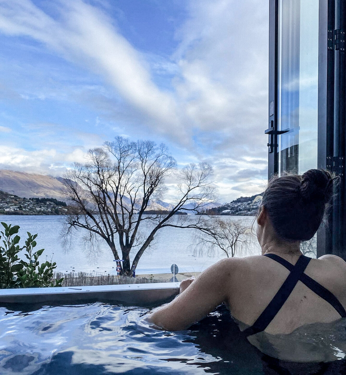 Young woman in dark blue bathing suit facing away from camera in Driftaway Queenstown hot tub