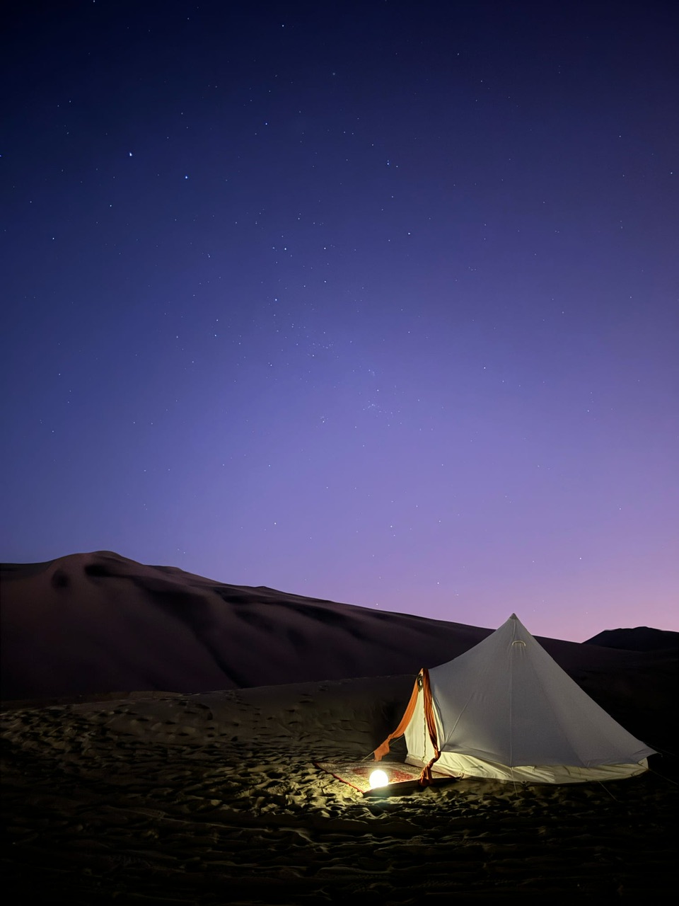 A white glamping tent under a purple sky at Duna Camp Glamping site in the Hauacachina Desert in Peru.