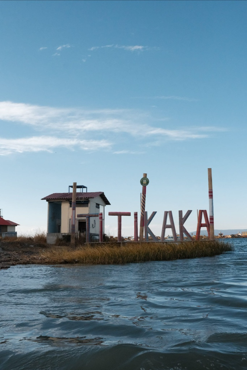 Wooden sign on an island pictured from a lake which reads "TITIKAKA"