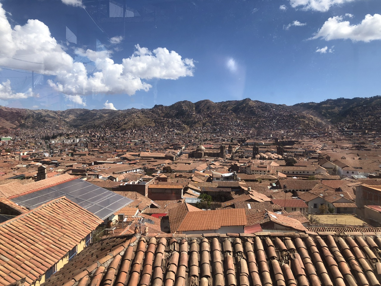 View over the city of Cusco showing rooftops and mountains in the background.