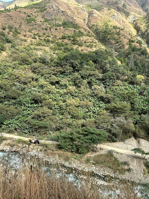 Young woman ziplining in Santa Maria Peru on Inca Adventure Trail to Machu Picchu. She is wearing black leggings and a strappy light pink singlet and yellow helmet.