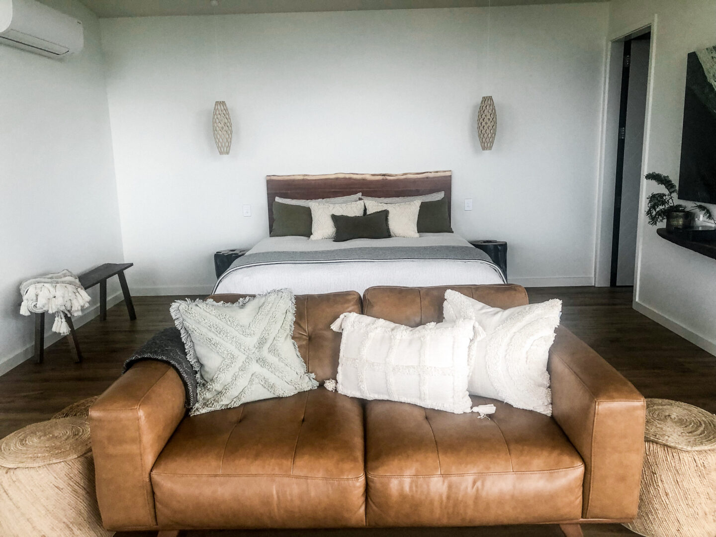 Canopy Camping Fossil Hill Hut interior with a large queen bed behind a brown leather couch.