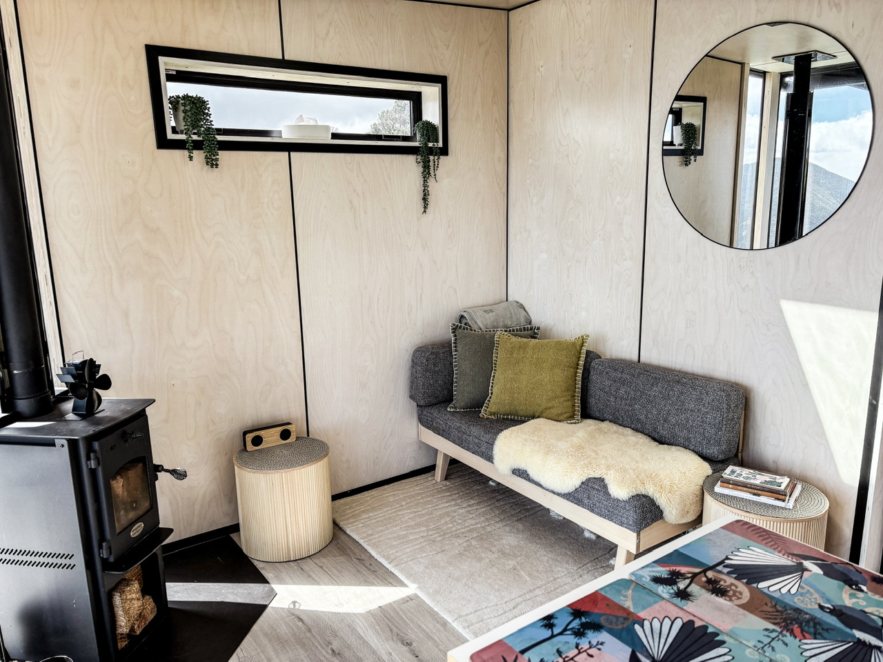 Living area at The Ocean House canopy camping site with a woodburner in the left corner and small couch.