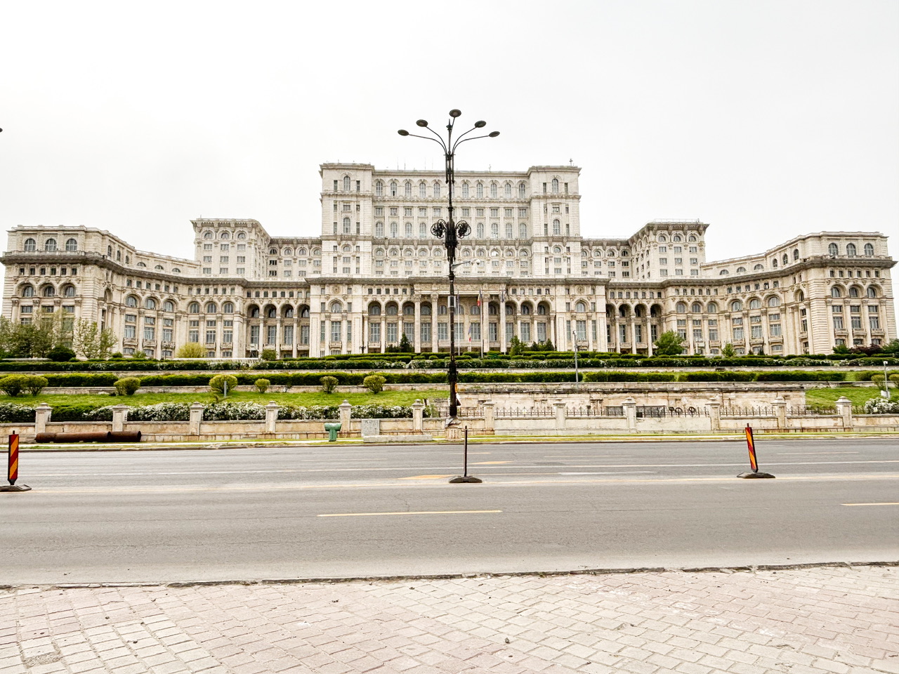 Large white Bucharest Palace of the Parliament building pictured from across a road.